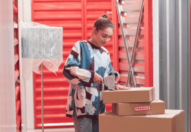 A young woman tapes up boxes to be held in her storage unit.
